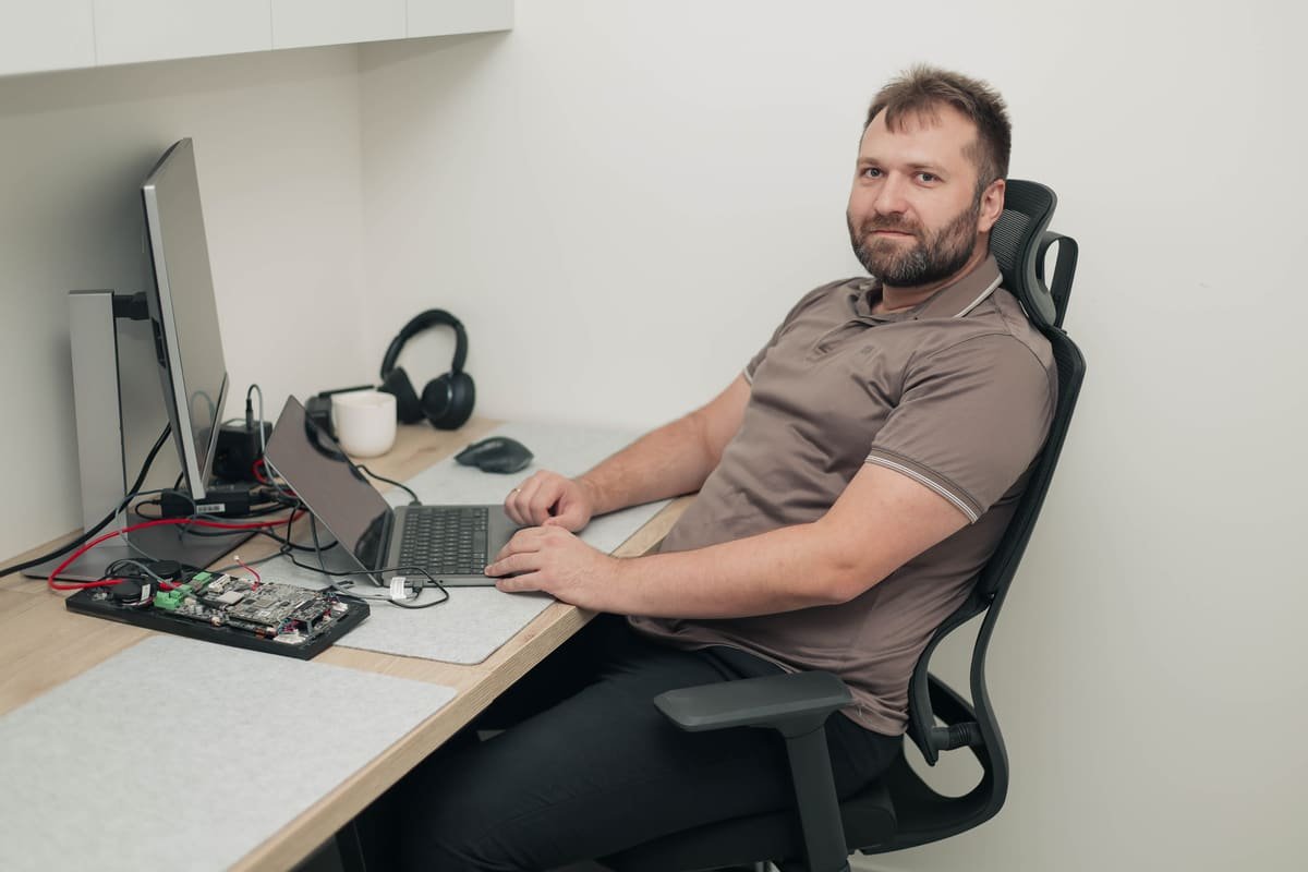 A TekPiq engineer at a desk with an embedded board, laptop and monitor