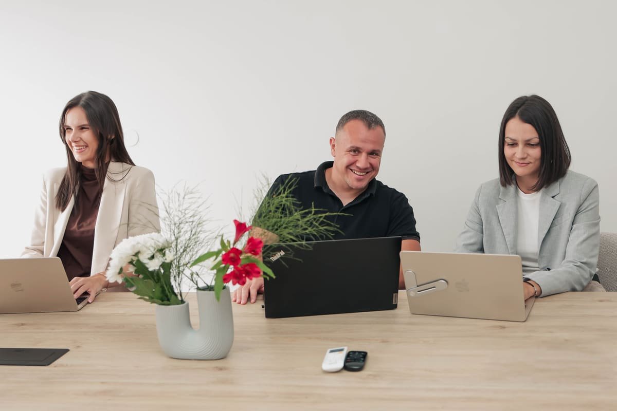Three TekPiq team members laughing during a meeting at the office conference table