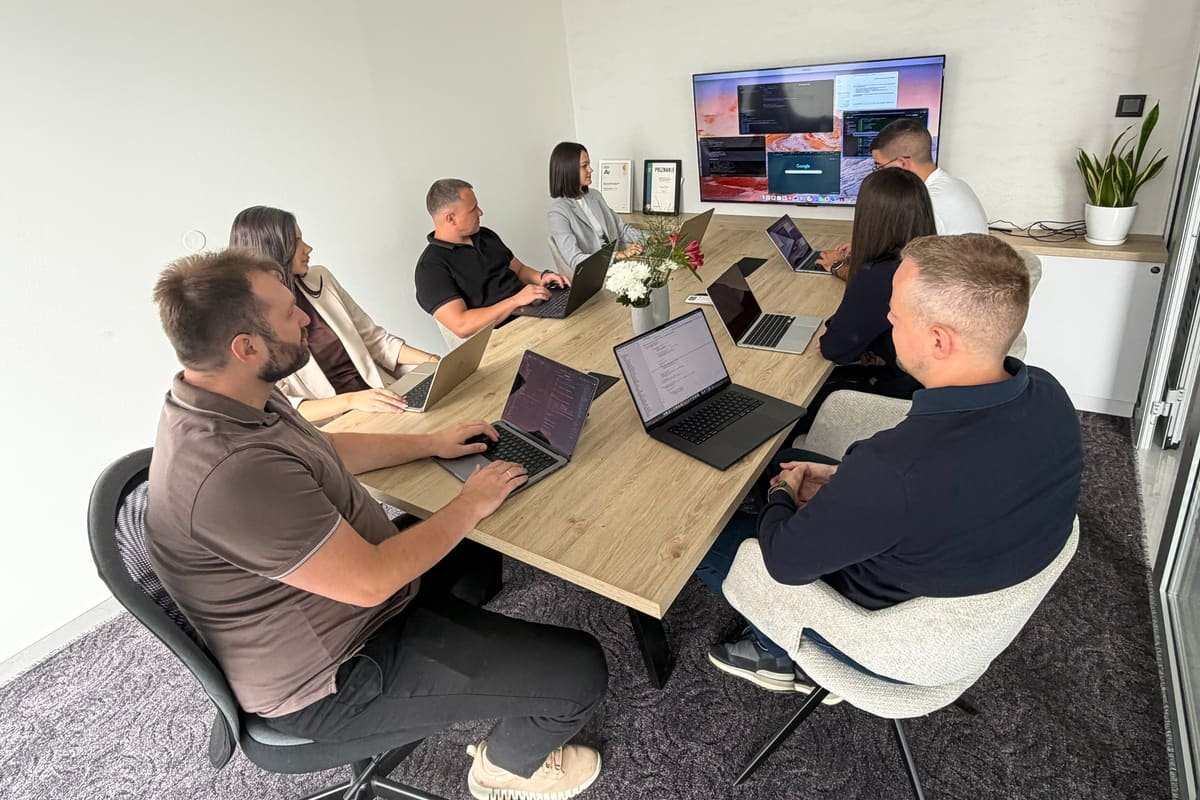 The TekPiq team around the meeting-room table with laptops, a shared screen on the wall