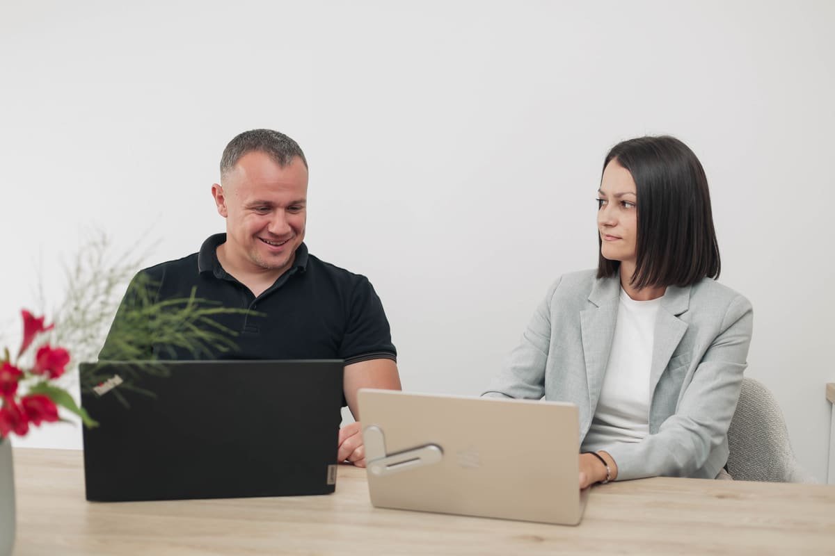 Two TekPiq colleagues pairing on laptops at the meeting table